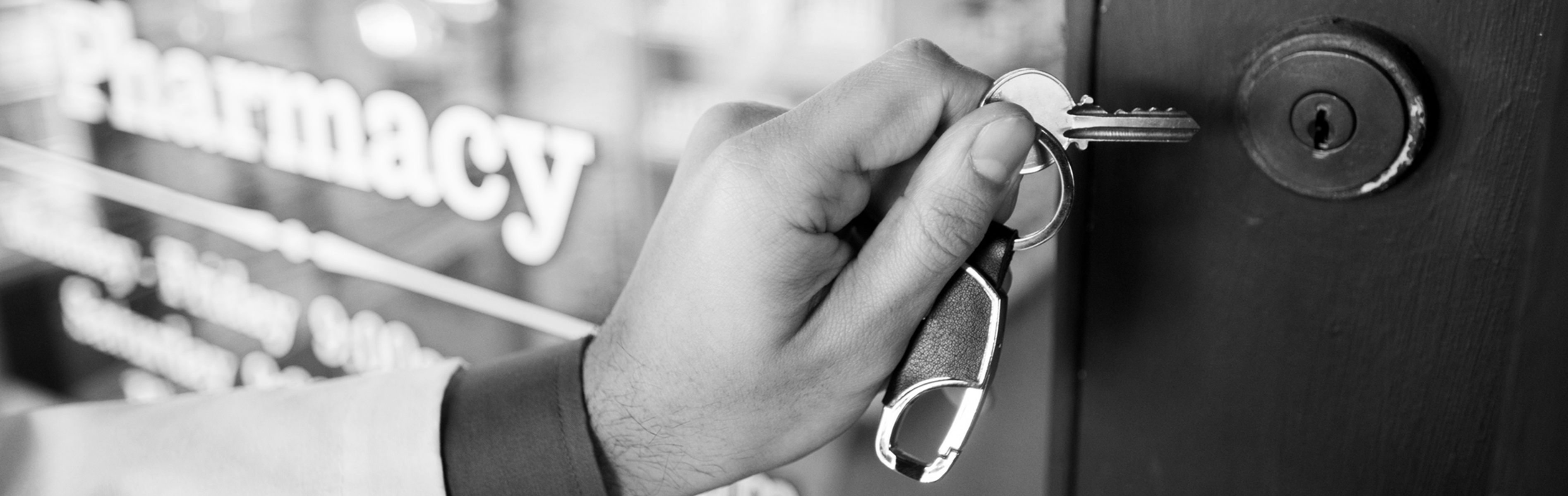 A pharmacist opens the door to his pharmacy