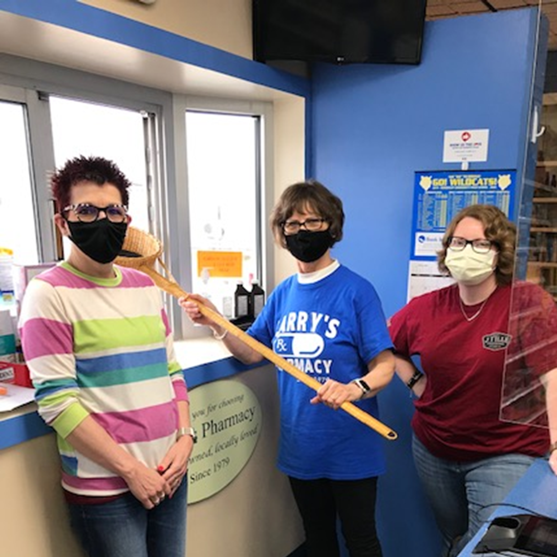 The team at Larry's Pharmacy using a church collection basket to conduct drive-thru transactions
