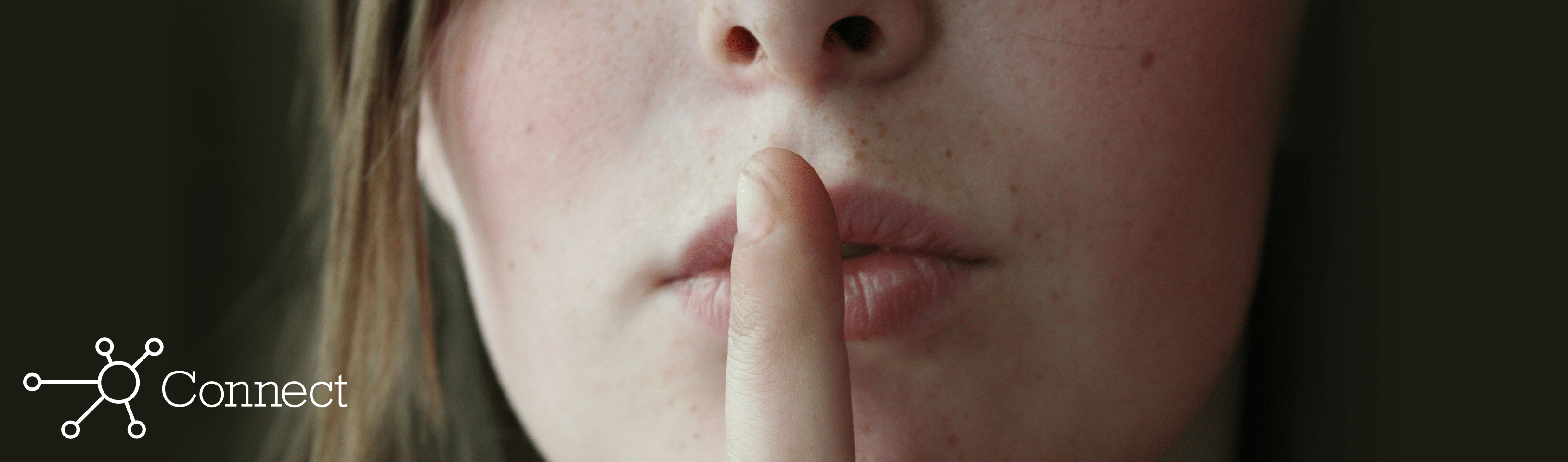 A woman holding her index finger up to her lips to hush someone